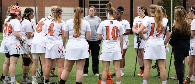 The women's lacrosse team in a huddle,