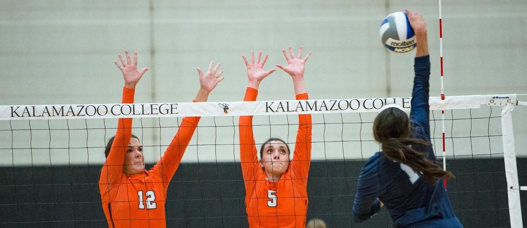 Kalamazoo College volleyball players jumping at the net.