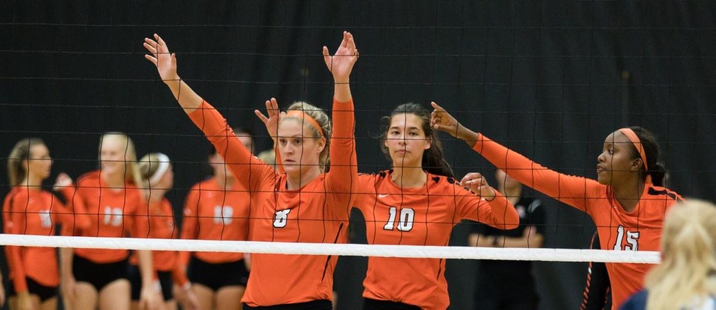 Kalamazoo College volleyball players at the net.