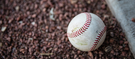 A baseball sitting on the dirt.