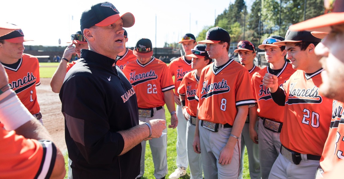 Head coach Mike Ott talking to the baseball team in a huddle.