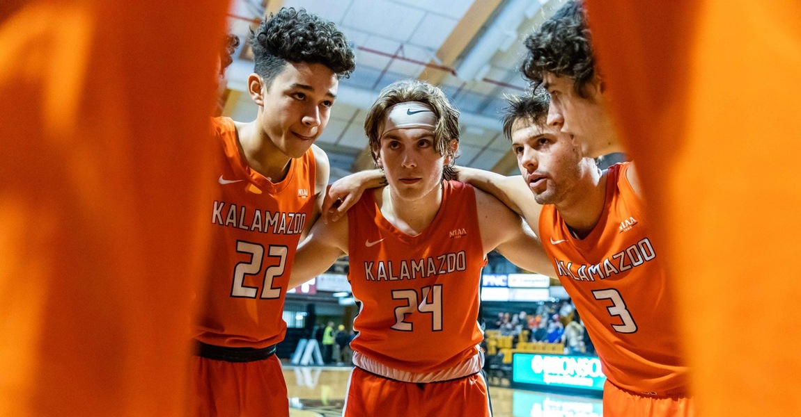 Kalamazoo College men's basketball players in a huddle.