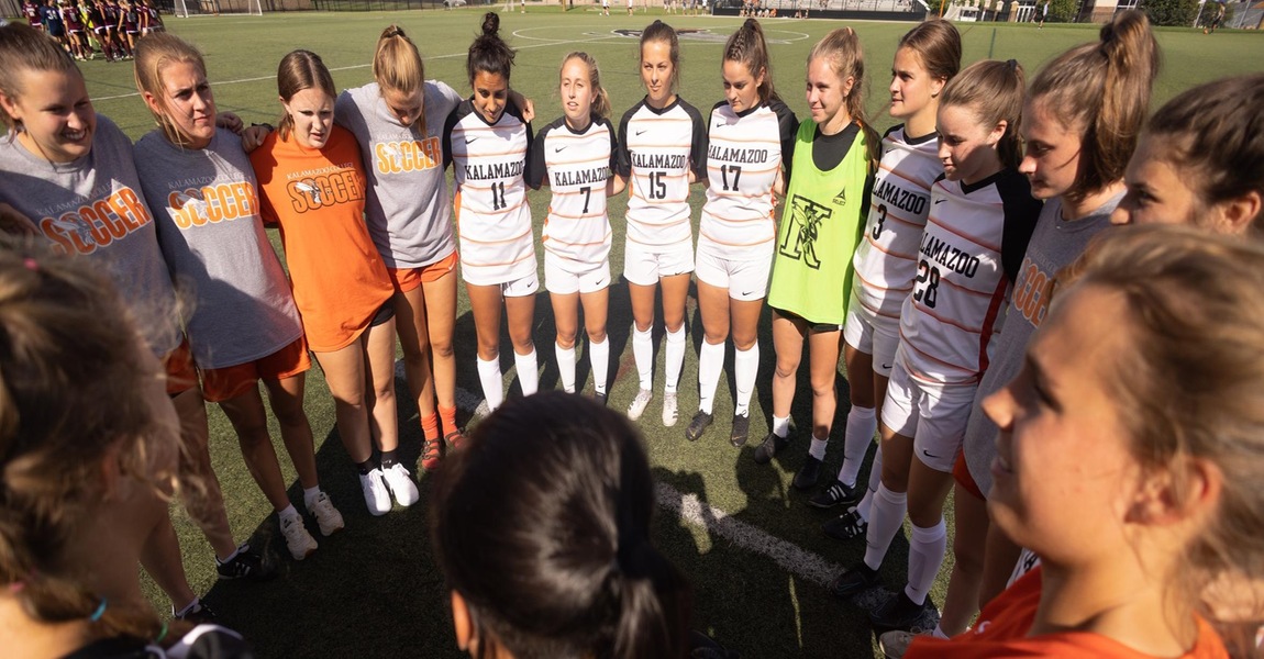 The women's soccer team is huddled before a game. 