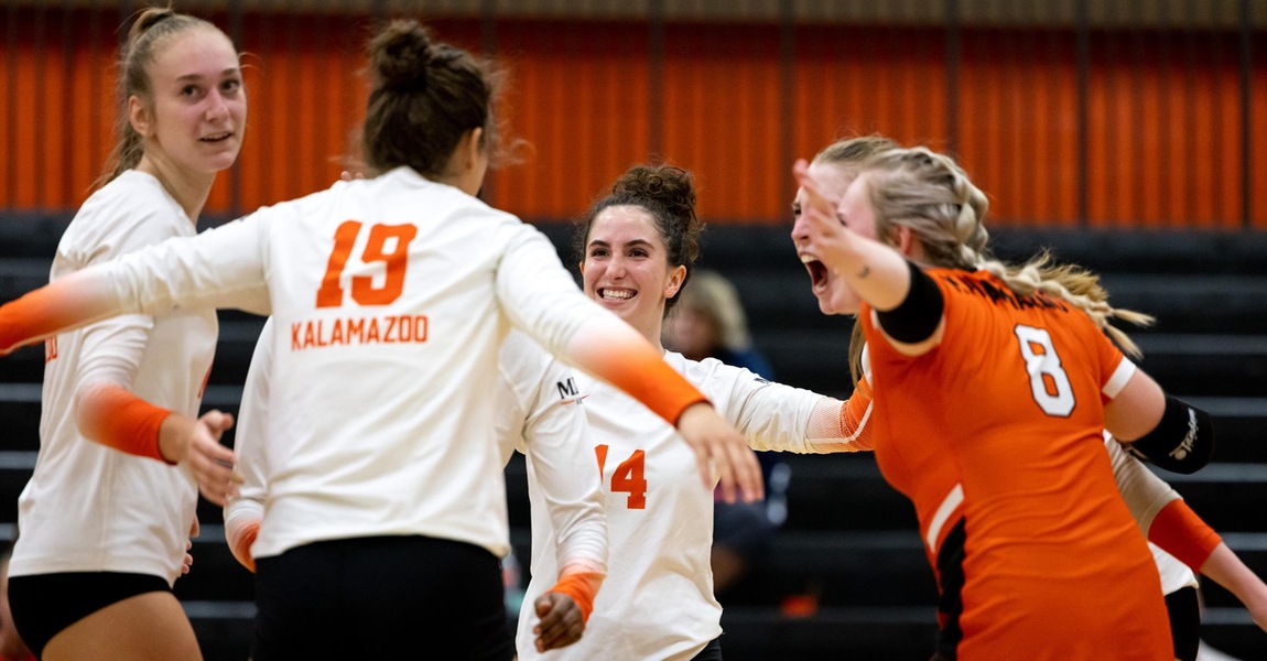 Kalamazoo College volleyball players celebrating on the court.